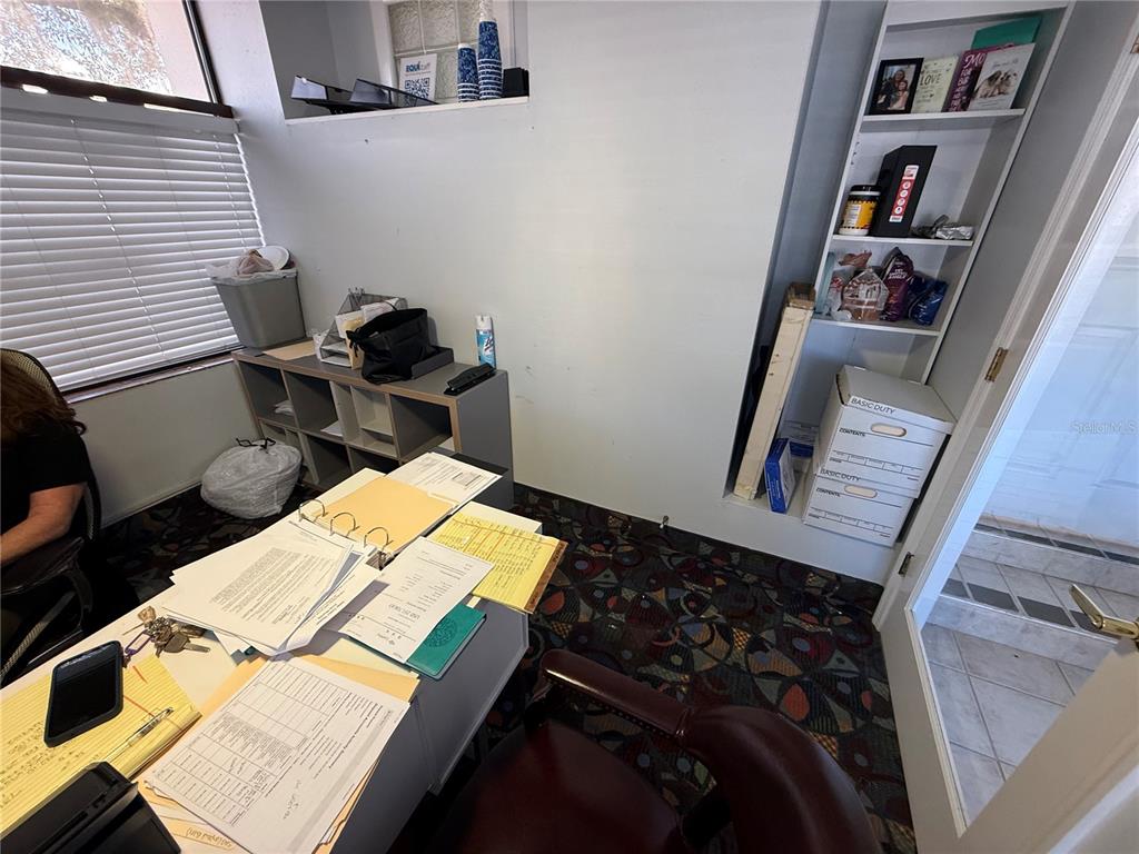 An office space features a desk with paperwork, a bookshelf, and a window with blinds — 1028 E SILVER SPRINGS BOULEVARD Bldg 1, OCALA, FL