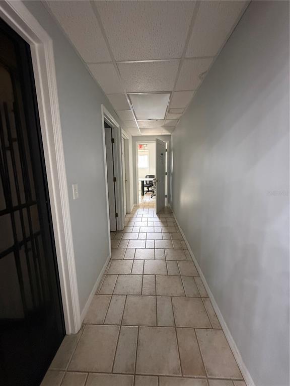A hallway with light blue walls, tiled flooring, and a drop ceiling leads to an office — 1028 E SILVER SPRINGS BOULEVARD Bldg 1, OCALA, FL