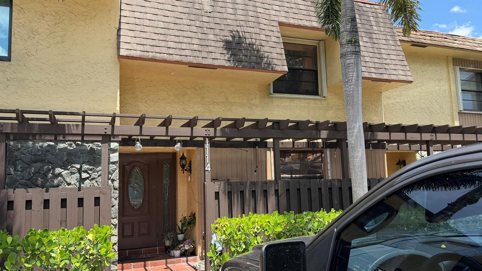 An exterior view of a two-story townhouse with a brown pergola and front door — 1114 NW 79th Drive, Plantation FL 33322, PLANTATION, FL