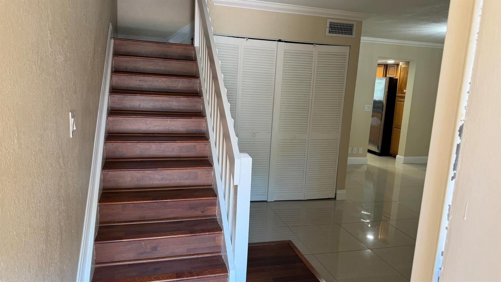 A staircase with wooden treads and a white railing sits next to white louvered closet doors — 1114 NW 79th Drive, Plantation FL 33322, PLANTATION, FL