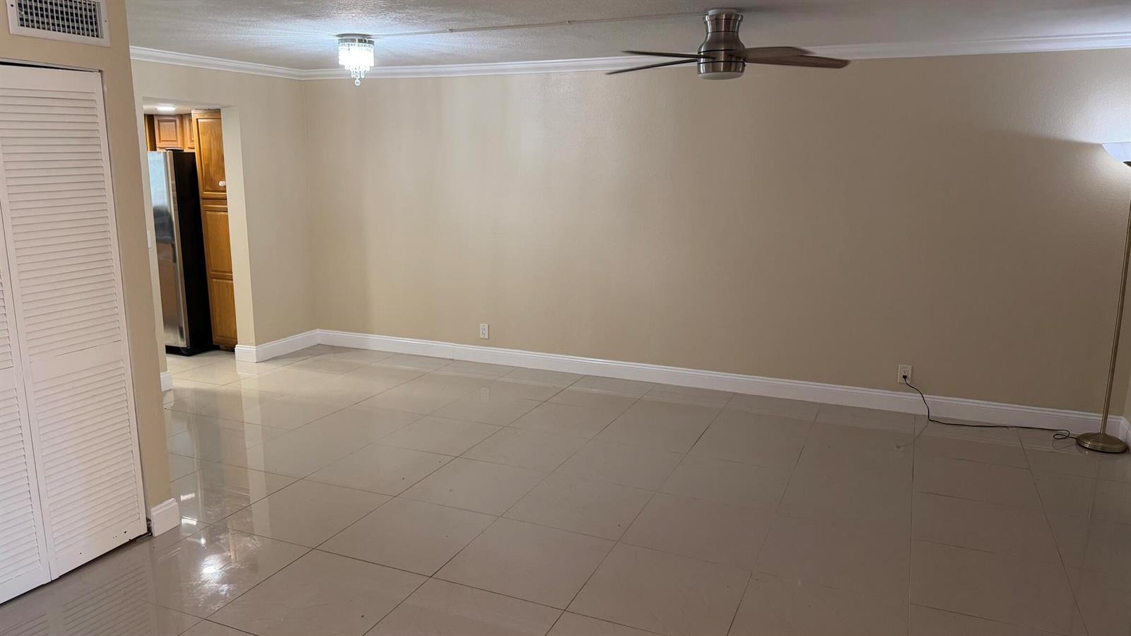 An empty room with beige walls, large floor tiles, a ceiling fan, and a chandelier — 1114 NW 79th Drive, Plantation FL 33322, PLANTATION, FL