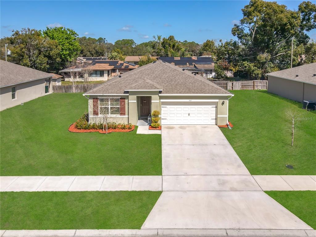 An exterior view of a single-story suburban house with a concrete driveway and green lawn — 712 RED HAWK LANE, DELTONA, FL