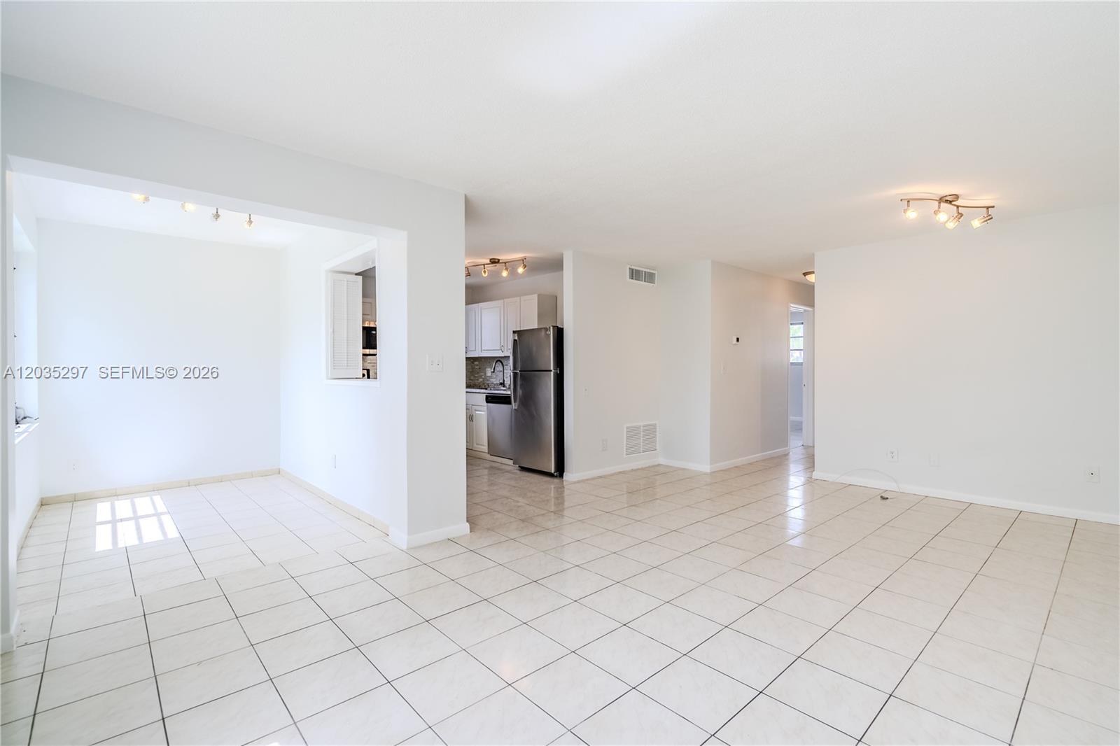 An open-concept living and dining area features white walls and light-colored tile flooring — 421 NE 1st St # 101, Hallandale Beach FL 33009, HALLANDALE BEACH, FL