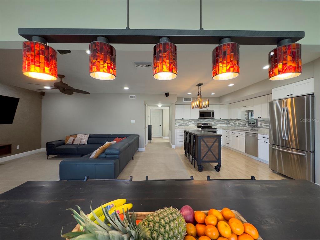 A kitchen and living area featuring a large island, stainless steel appliances, and pendant lighting — 559 B FAIRWAYS CIRCLE, OCALA, FL
