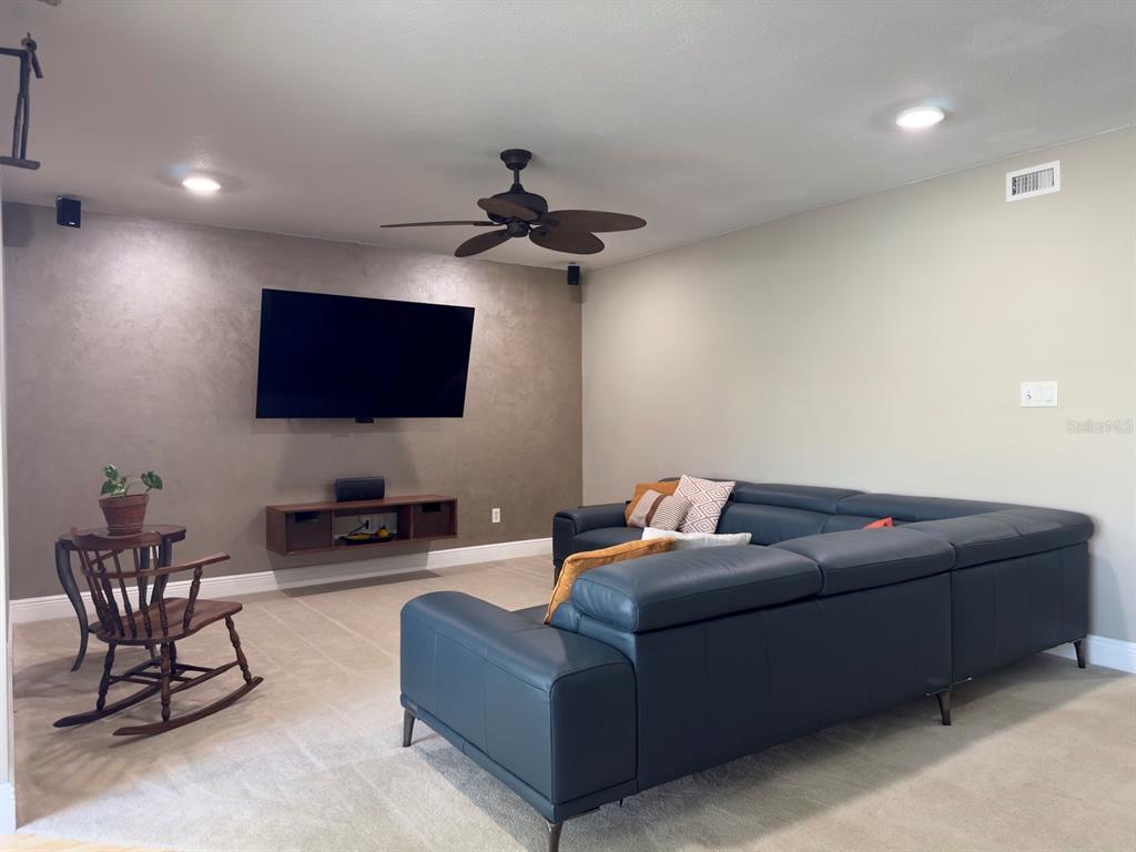 A living room features a dark accent wall with a mounted television and sectional sofa — 559 B FAIRWAYS CIRCLE, OCALA, FL
