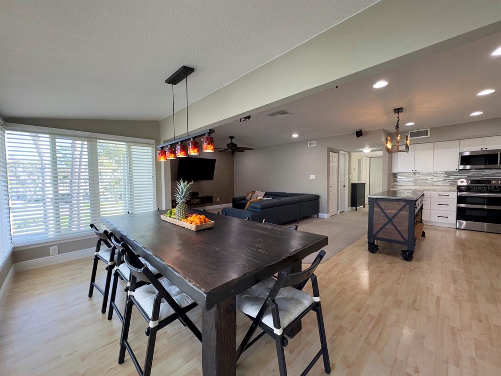 An open-concept dining area with a dark wood table leads into a living room and kitchen — 559 B FAIRWAYS CIRCLE, OCALA, FL