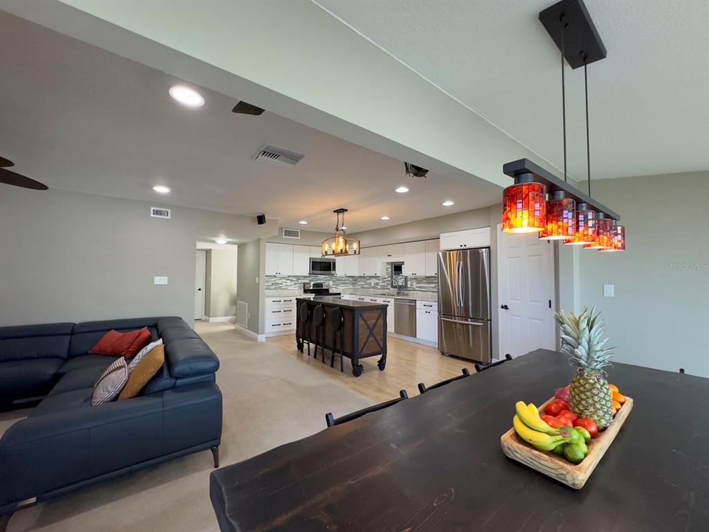 An open-concept kitchen and living area features a dark sofa, kitchen island, and dining table — 559 B FAIRWAYS CIRCLE, OCALA, FL