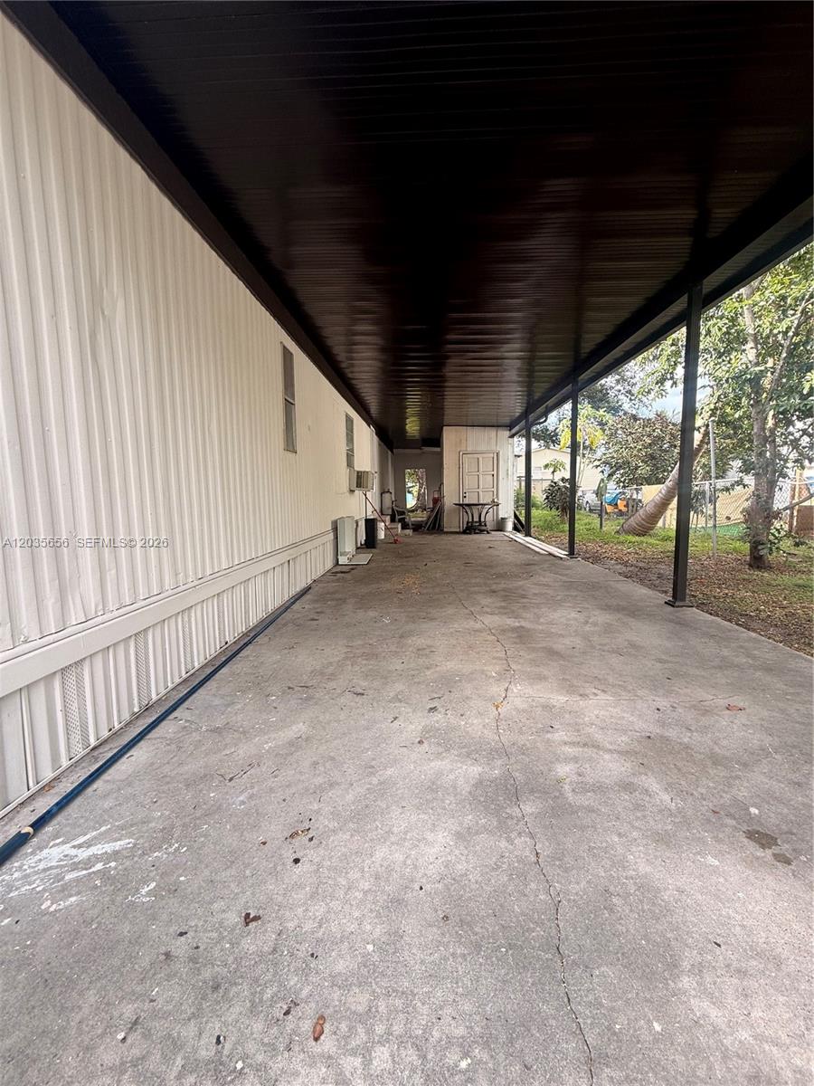 A long, covered concrete carport runs alongside the exterior wall of a mobile home — 607 Sabal ave, Clewiston FL 33440, CLEWISTON, FL