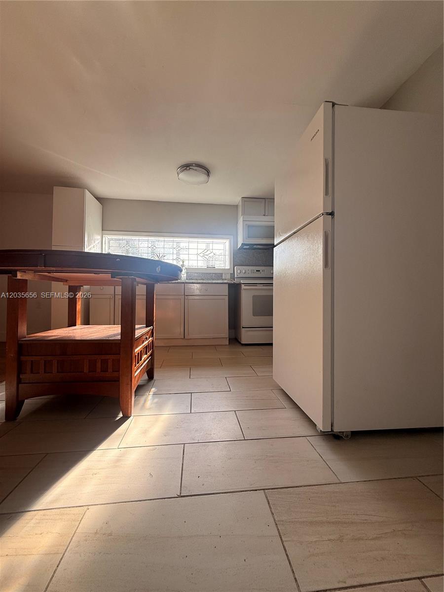 A kitchen features white cabinets, light tile flooring, and a large white refrigerator — 607 Sabal ave, Clewiston FL 33440, CLEWISTON, FL