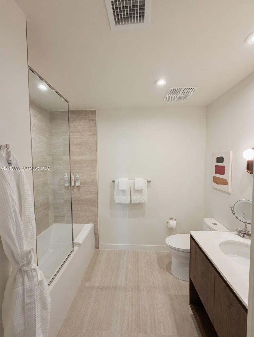 A modern bathroom features a glass-enclosed tub, a vanity, and a toilet on tiled flooring — 1611 SW 2nd Ave # 707, Miami FL 33129, MIAMI, FL