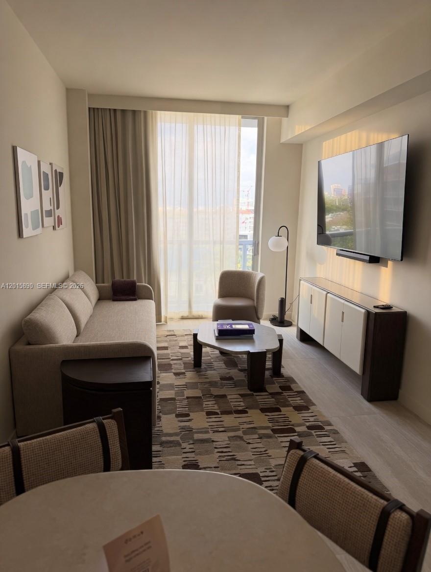 A living room features a sofa, coffee table, armchair, media console, and a large television — 1611 SW 2nd Ave # 707, Miami FL 33129, MIAMI, FL