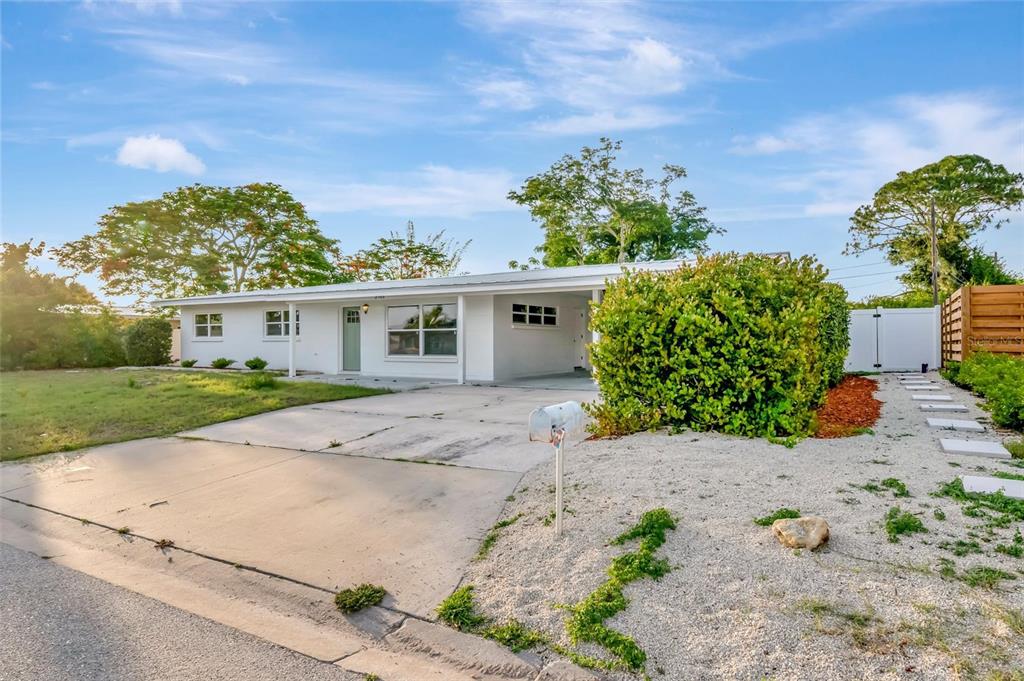 A white single-story house features a concrete driveway, a carport, and a gravel front yard — 2705 SUNNYSIDE STREET, SARASOTA, FL