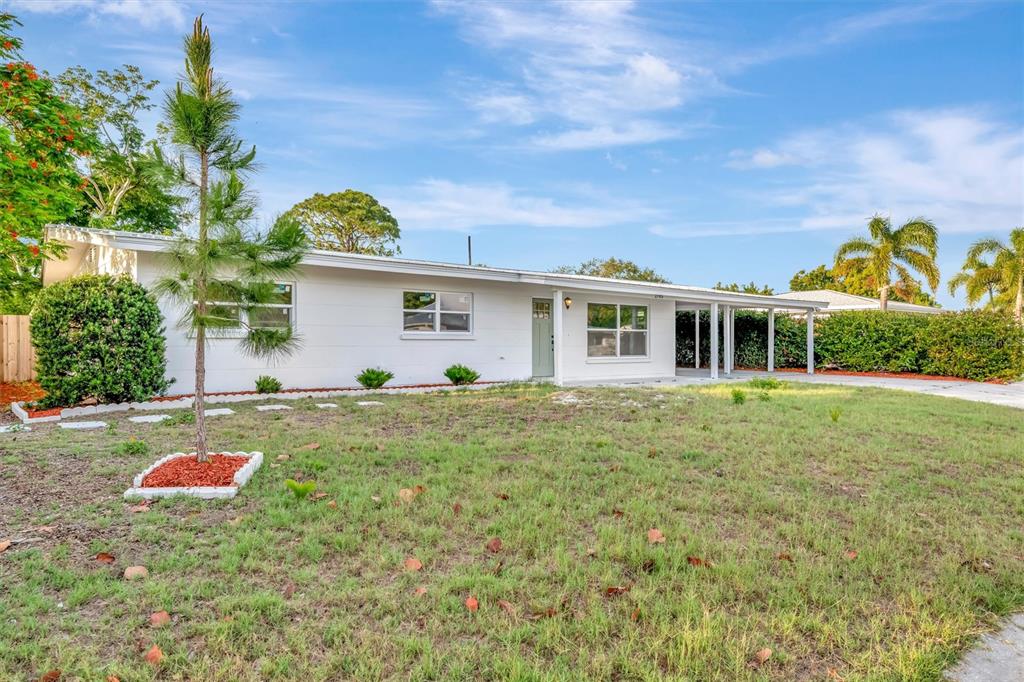 A single-story white house with a covered carport and a front yard with trees — 2705 SUNNYSIDE STREET, SARASOTA, FL
