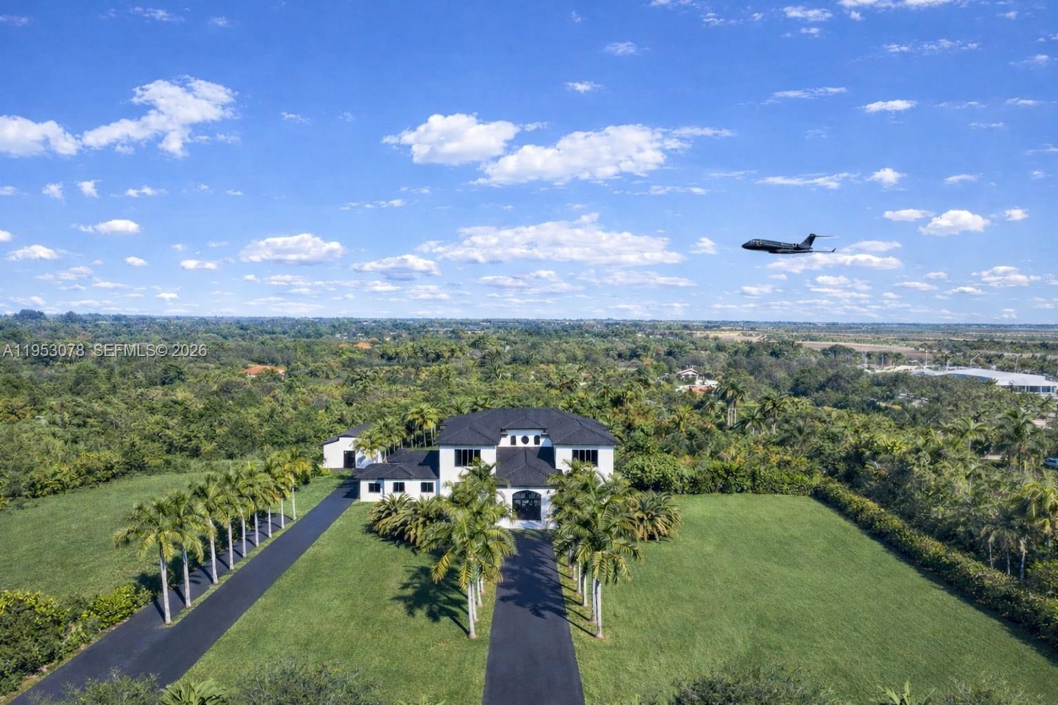 An aerial view shows a white house with a black roof and palm-lined driveways — 17805 SW 158th St, Miami FL 33187, MIAMI, FL