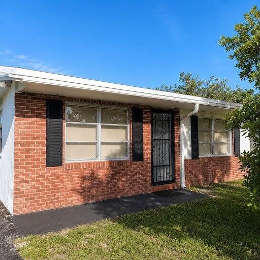 A single-story brick house with a white roofline, black shutters, and a metal security door — 1030 NW 73rd Avenue, Margate FL 33063, MARGATE, FL