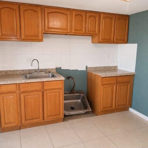 A kitchen features oak cabinets, a tiled backsplash, and a sink sitting on the floor — 1030 NW 73rd Avenue, Margate FL 33063, MARGATE, FL