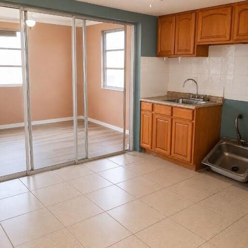 A kitchen area with wooden cabinets, a sink, and a sliding glass door to another room — 1030 NW 73rd Avenue, Margate FL 33063, MARGATE, FL