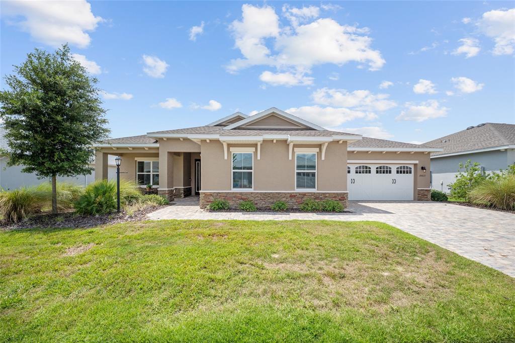 A single-story house with a stone-accented facade, a paved driveway, and a two-car garage — 10621 SW 98TH LANE, OCALA, FL