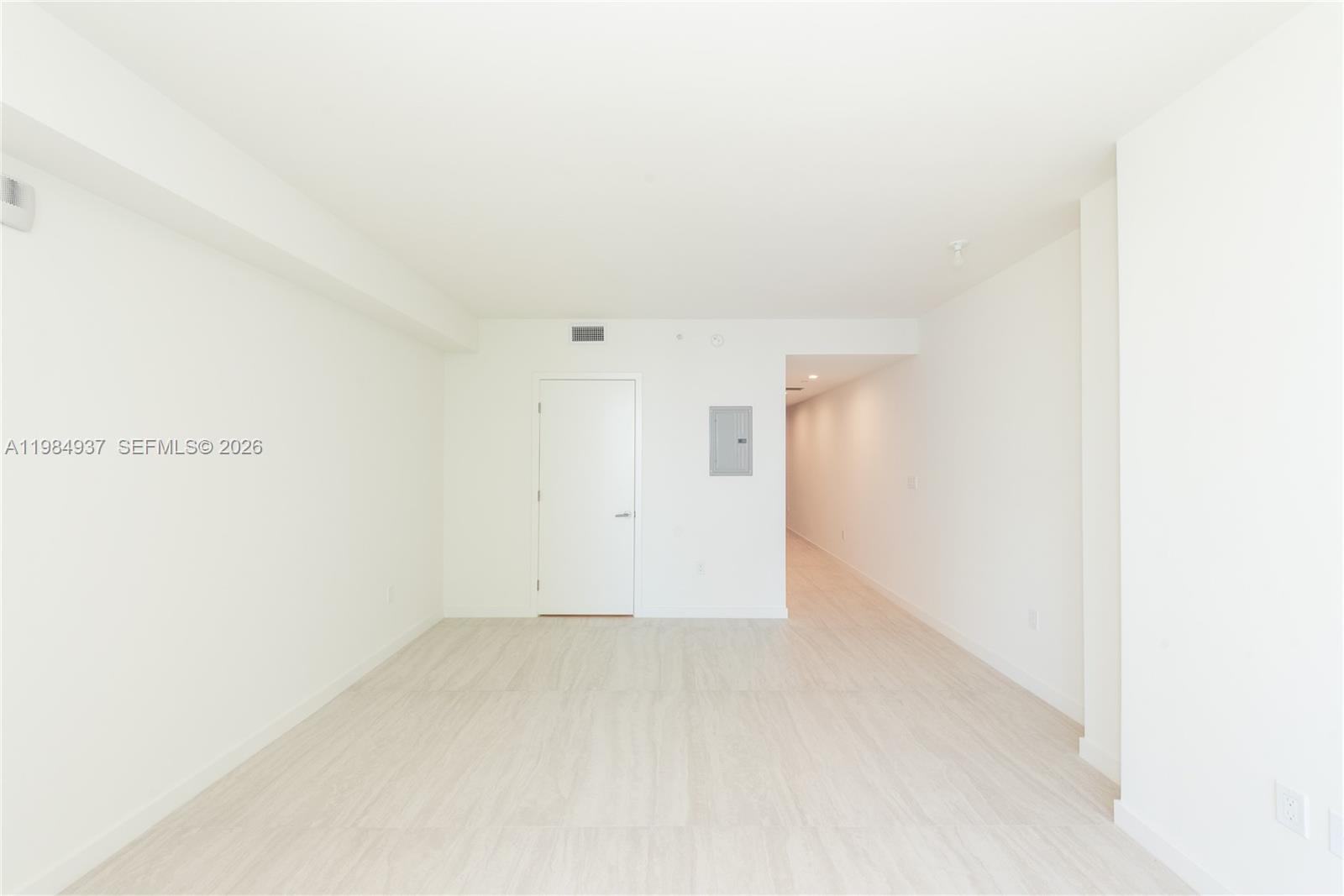 An empty room features white walls, light-colored flooring, a single door, and a hallway entrance — 77 SE 5th Street # 4004, Miami FL 33131, MIAMI, FL
