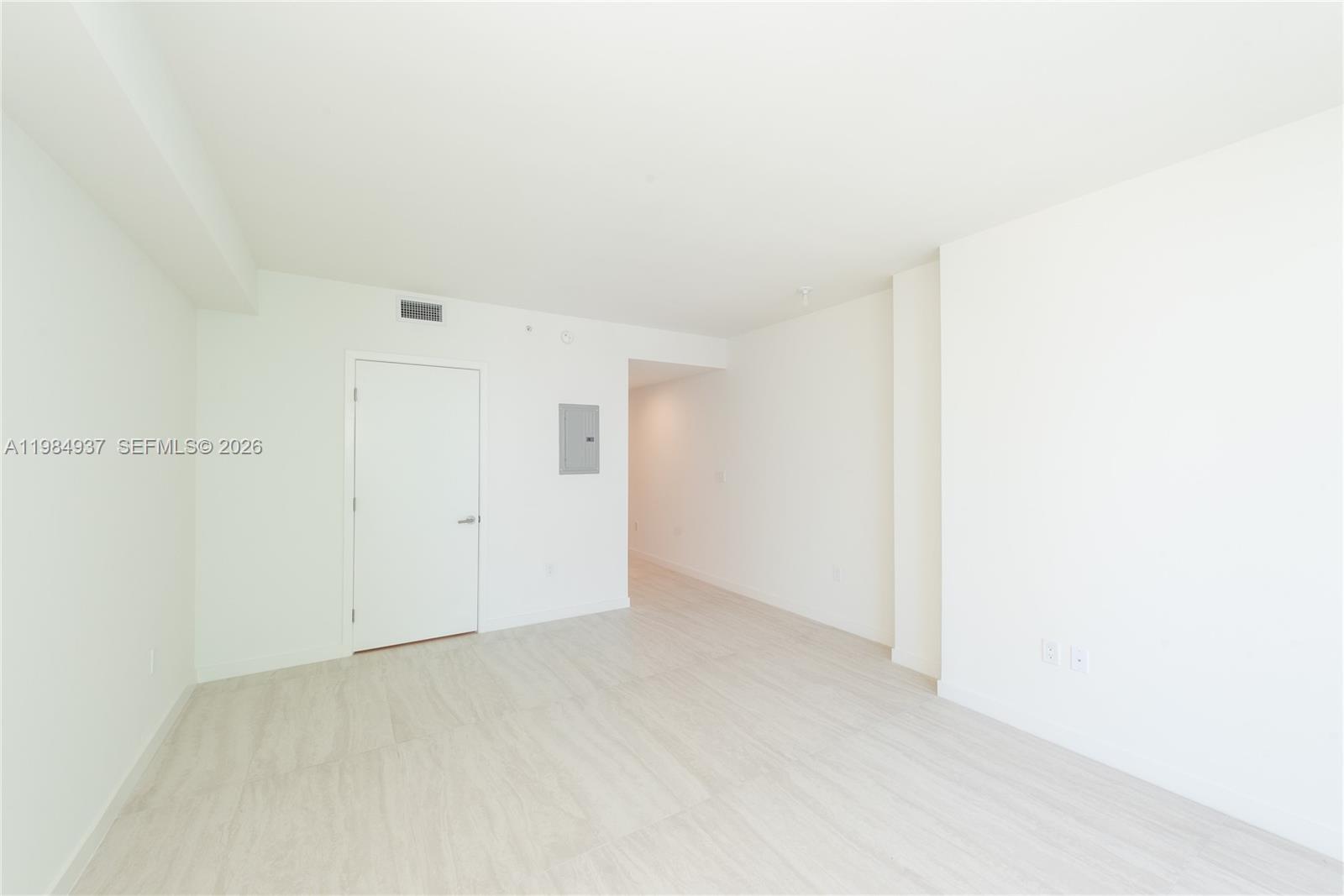 An empty room features white walls, light-colored tile flooring, and a single closed door — 77 SE 5th Street # 4004, Miami FL 33131, MIAMI, FL