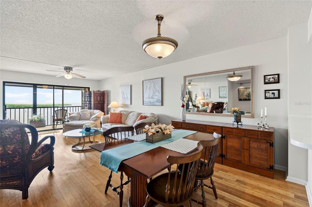 A dining area with a wooden table and chairs sits adjacent to a living room — 4650 BAY BOULEVARD UNIT 1044, PORT RICHEY, FL