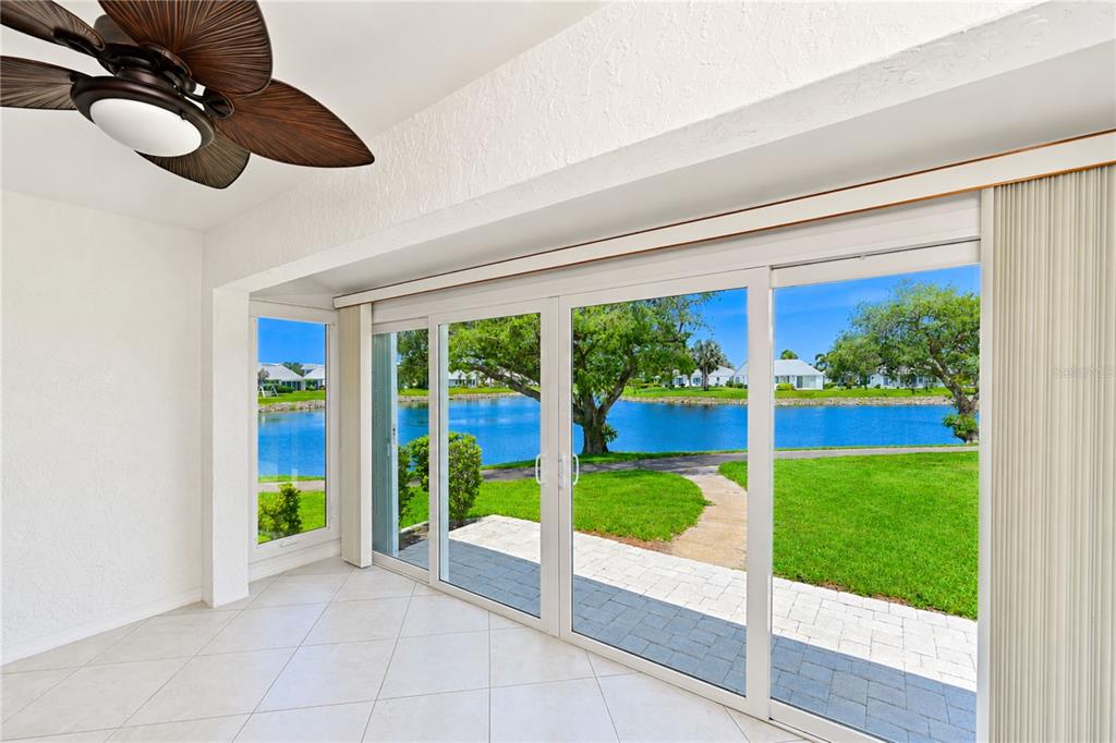 A bright room with tile floors and a ceiling fan overlooks a lake through sliding doors — 9425 ANDOVER CIRCLE, BRADENTON, FL