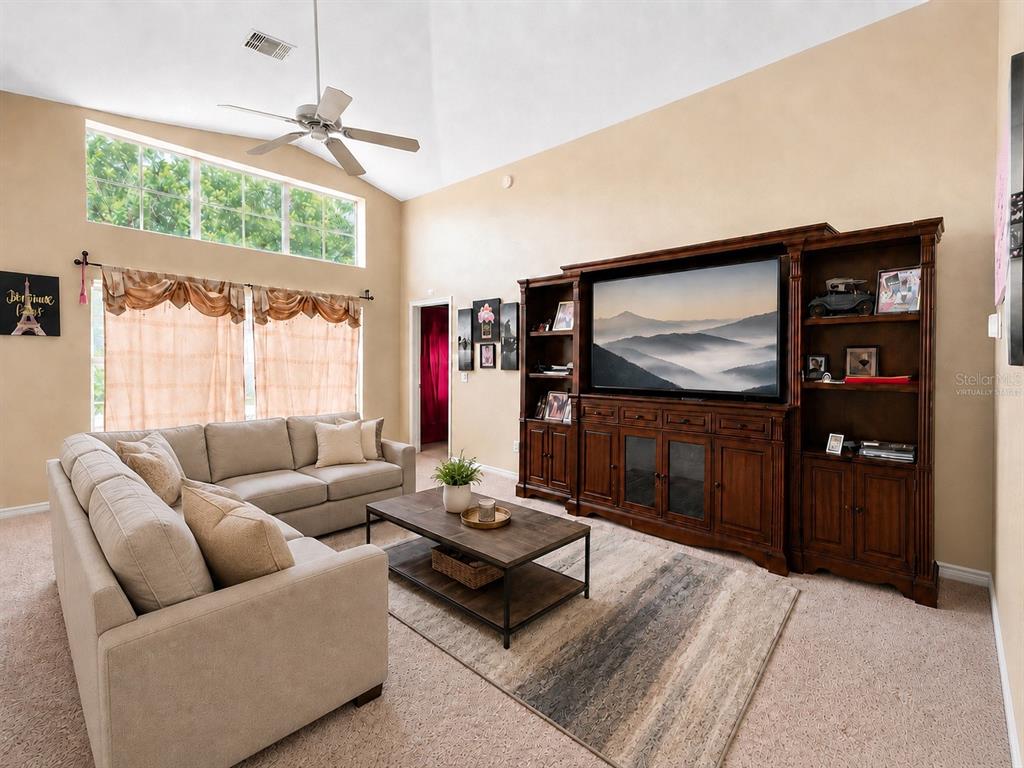 A living room features a beige sectional sofa, a wooden entertainment center, and vaulted ceilings — 531 SILVER PALMS CIRCLE, DAVENPORT, FL
