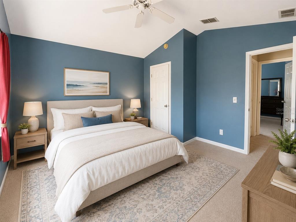 A bedroom with blue walls, a beige upholstered bed, and a ceiling fan — 531 SILVER PALMS CIRCLE, DAVENPORT, FL
