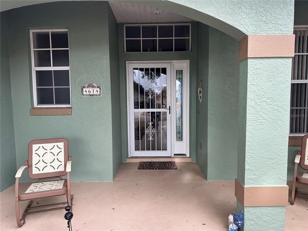 A covered front porch features a screen door, a house number plaque, and two chairs — 4614 N CRESTLINE DRIVE, BEVERLY HILLS, FL