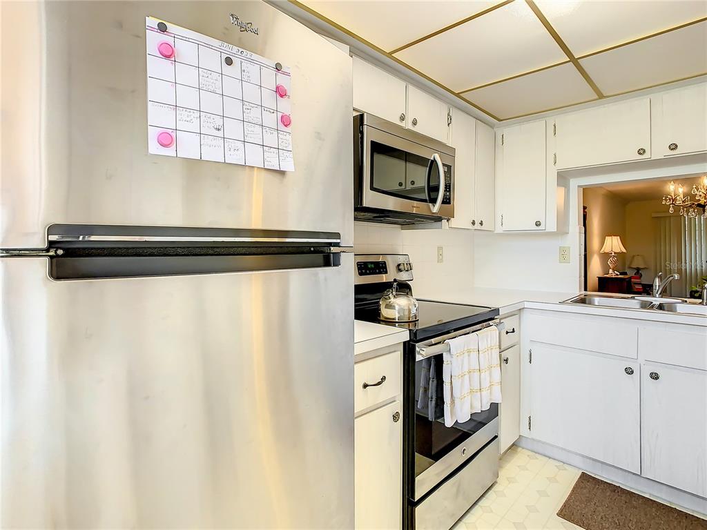 A kitchen features white cabinetry, stainless steel appliances, and a calendar on the refrigerator — 4230 REDCLIFF PLACE UNIT 4230, NEW PORT RICHEY, FL