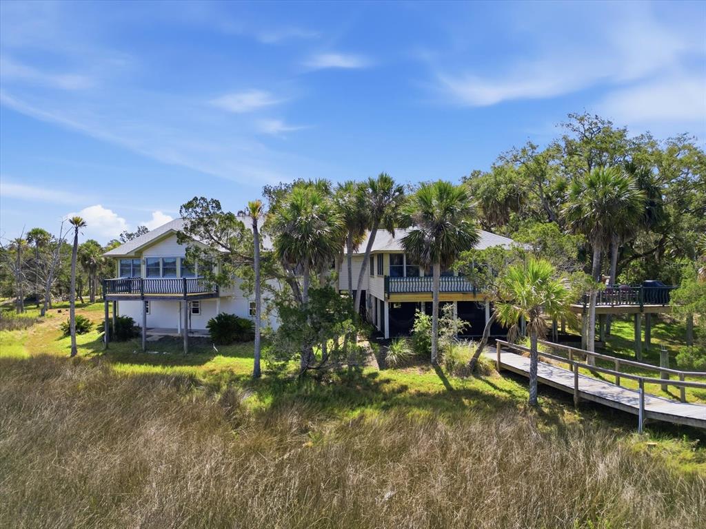 An aerial view shows a house nestled in trees with a long dock over water — 12350 W RED MAPLE STREET, HOMOSASSA, FL