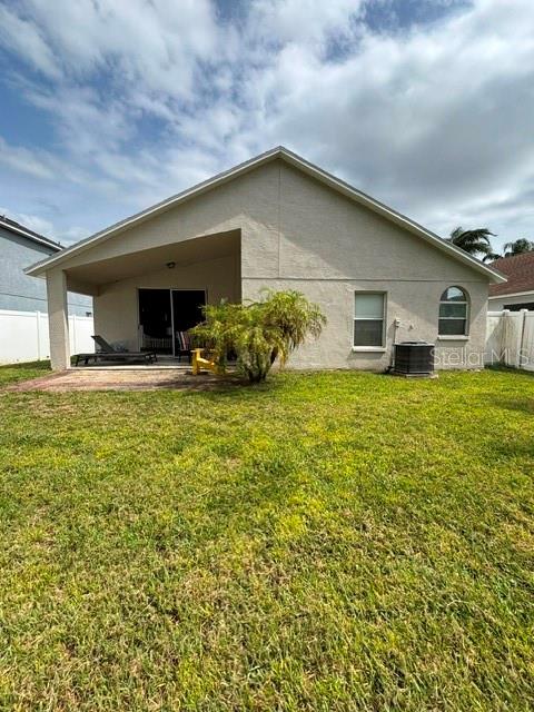 The exterior of a beige house features a covered patio and a grassy backyard — 4304 STONES RIVER COURT, NEW PORT RICHEY, FL