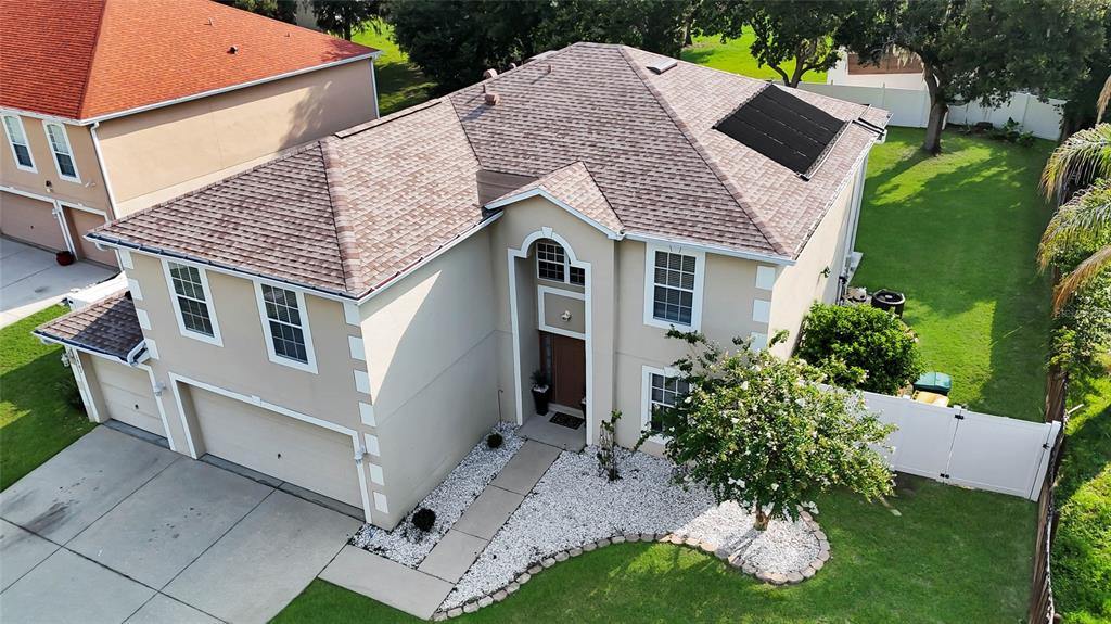 An aerial view shows a two-story suburban house with a tan stucco exterior and roof — 1702 FOREST GLEN DRIVE, FRUITLAND PARK, FL