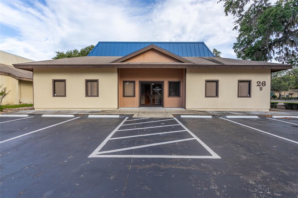 A single-story commercial building with a blue metal roof and a paved parking lot — 26 OFFICE PARK DRIVE, PALM COAST, FL