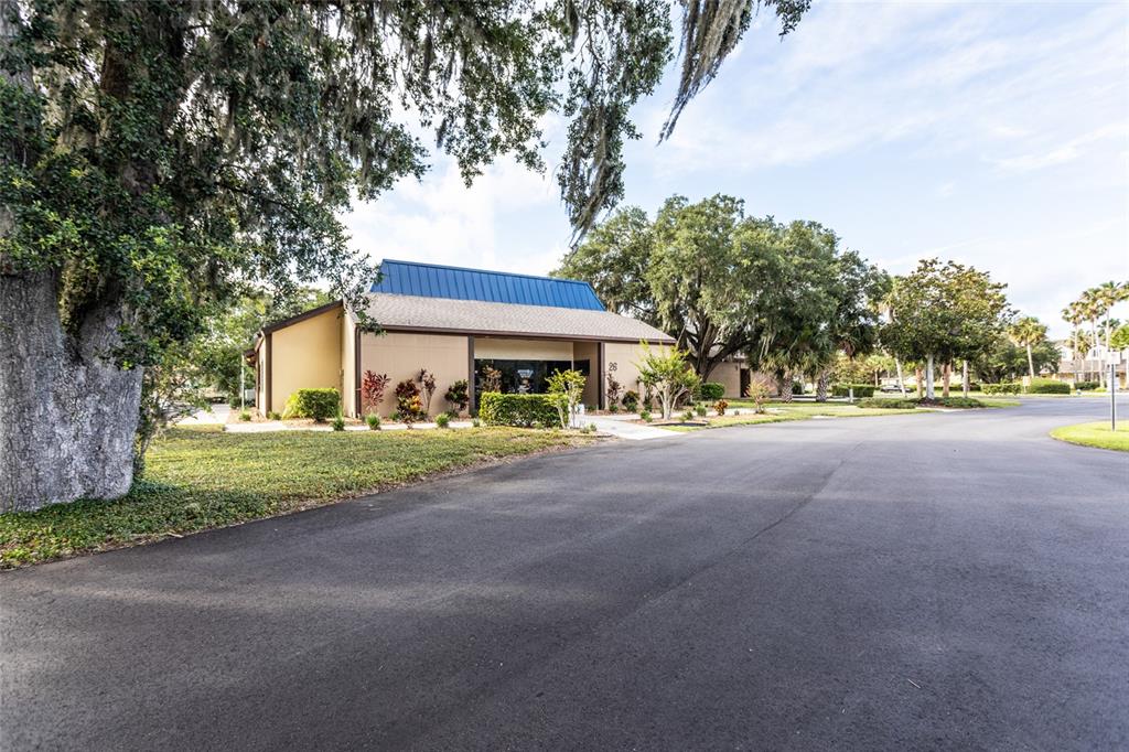 A tan commercial building with a blue metal roof sits beside a paved road — 26 OFFICE PARK DRIVE, PALM COAST, FL