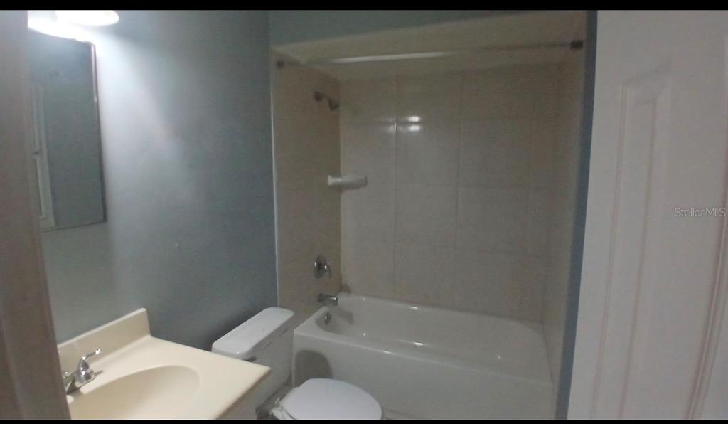 A bathroom features a vanity, a toilet, and a shower-tub combination with light-colored wall tiles — 5607 CHET DRIVE, ORLANDO, FL