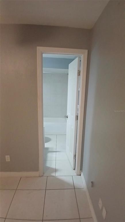 A doorway leads from a tiled room into a bathroom with a white tub and shower — 5607 CHET DRIVE, ORLANDO, FL
