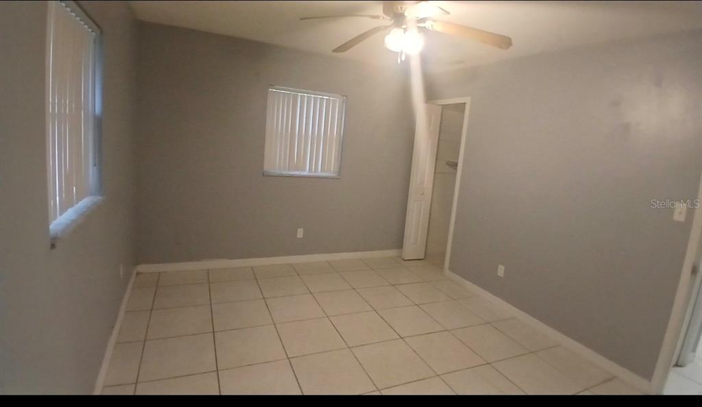 An empty bedroom features light gray walls, white tile flooring, and a ceiling fan — 5607 CHET DRIVE, ORLANDO, FL