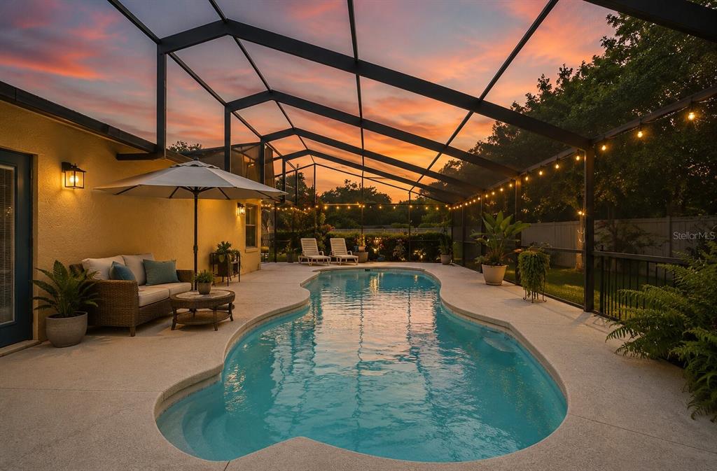 A screened-in patio features a swimming pool, outdoor seating, and string lights at sunset — 41300 DIXIE AVENUE, UMATILLA, FL