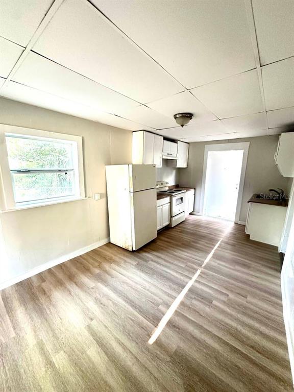 A kitchen features white cabinets, a white refrigerator, a stove, and light wood-look flooring — 404 PENNSYLVANIA AVENUE, CLEARWATER, FL