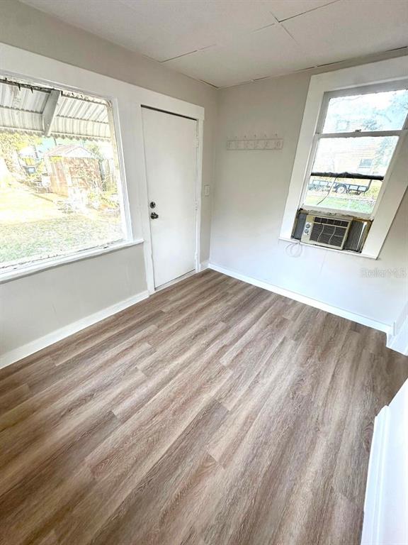 A room with light-colored walls, wood-look flooring, a white door, and a window air conditioner — 404 PENNSYLVANIA AVENUE, CLEARWATER, FL