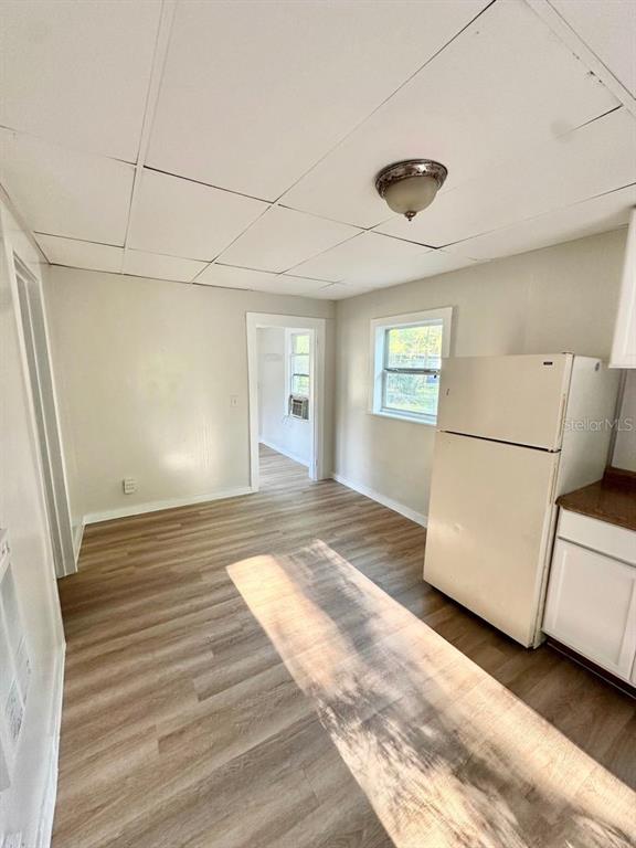 A kitchen with light-colored walls, wood-look flooring, a white refrigerator, and a drop ceiling — 404 PENNSYLVANIA AVENUE, CLEARWATER, FL