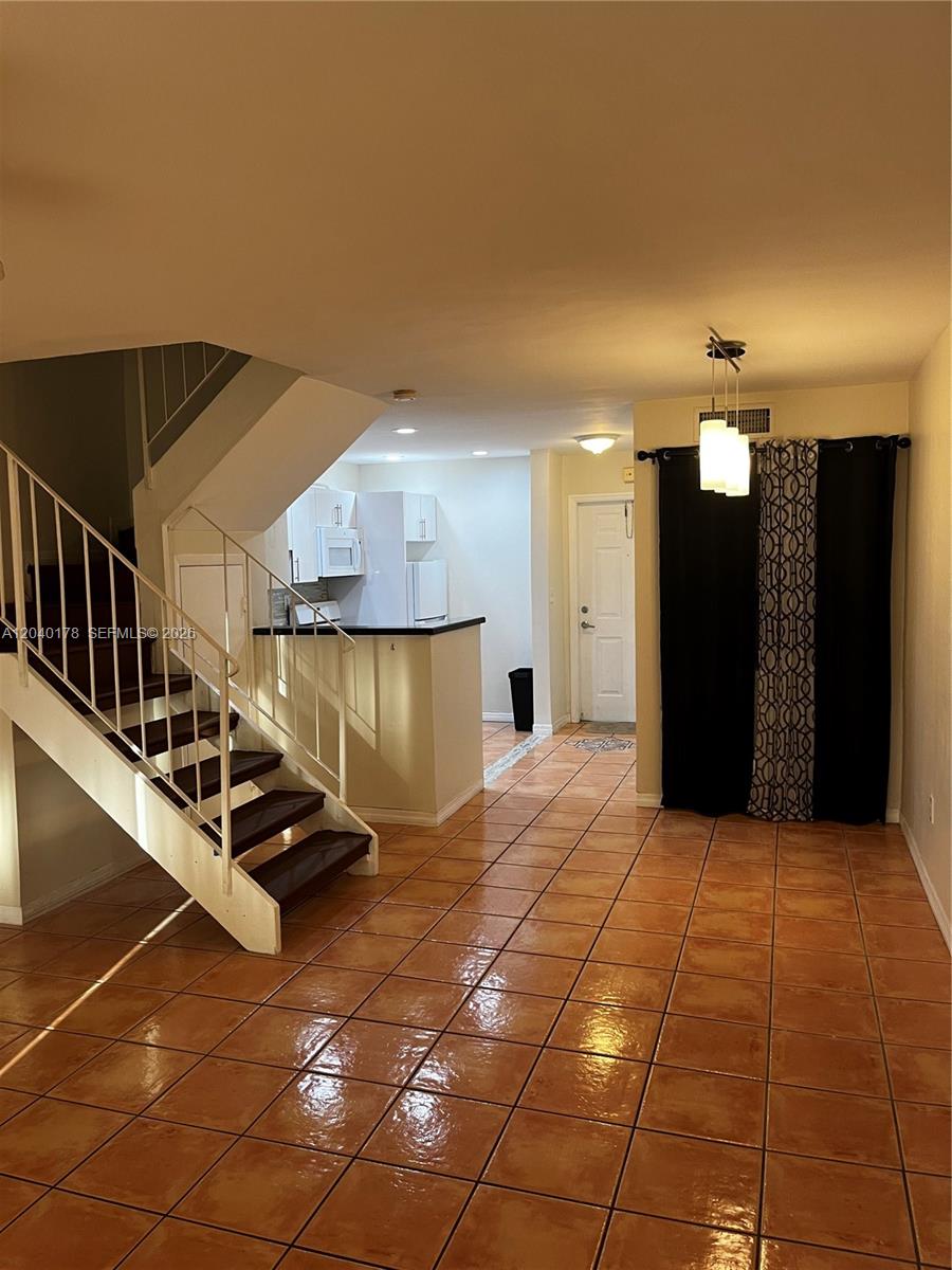 An interior view shows a tiled living area with a staircase and an open kitchen — 8650 SW 67th Ave # 1029, Pinecrest FL 33156, PINECREST, FL
