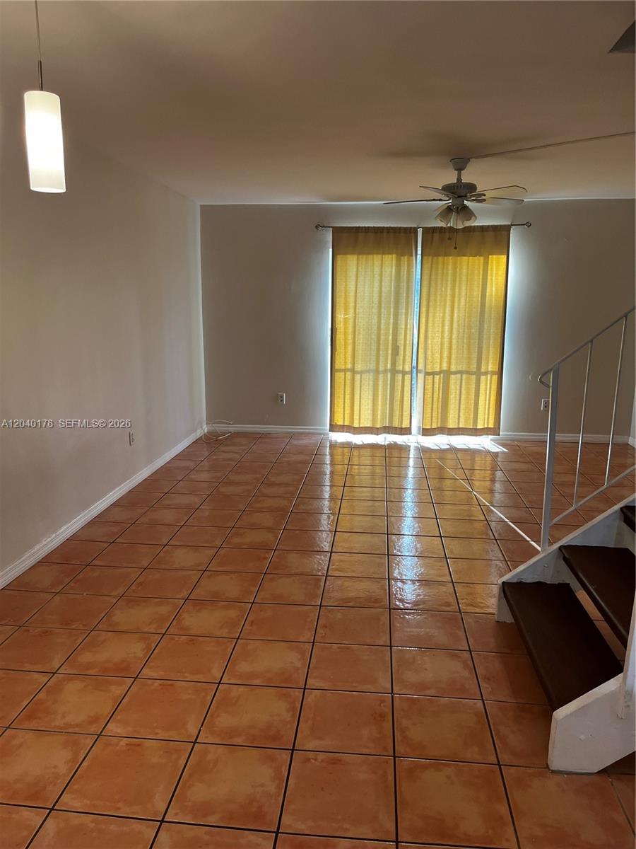 An empty room features terracotta tile flooring, a ceiling fan, and a sliding glass door — 8650 SW 67th Ave # 1029, Pinecrest FL 33156, PINECREST, FL