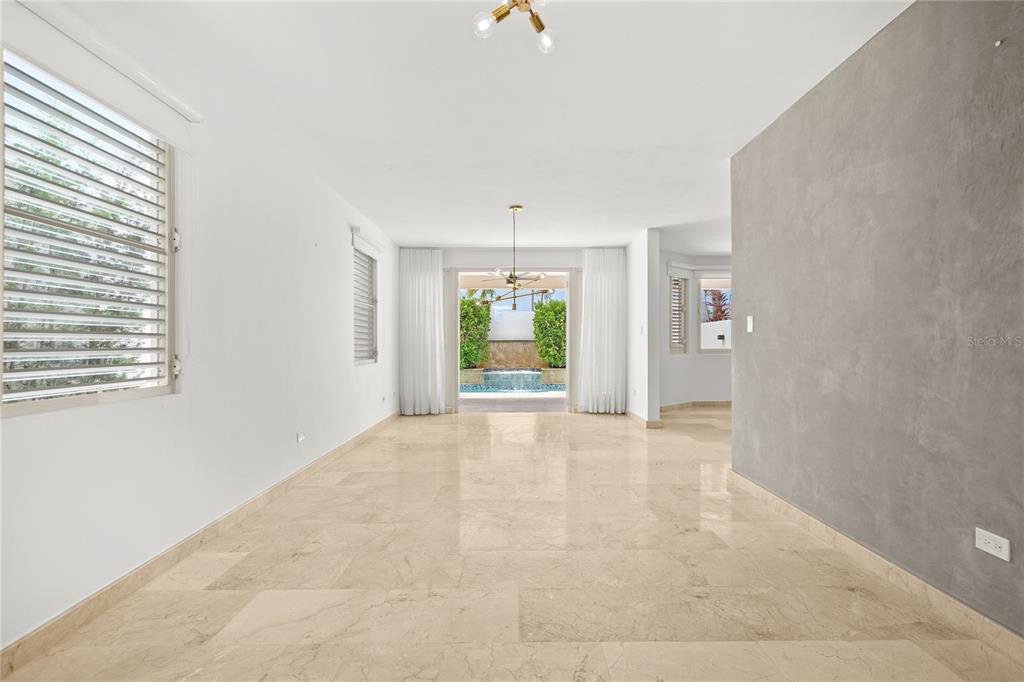 A bright, empty living room features marble floors, a textured gray wall, and sliding glass doors — J9 CALLE NATALIA, TRUJILLO ALTO, PR