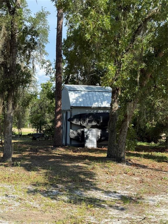 A small metal storage shed sits among trees with two kayaks stored on its side — 108 KITTY AVENUE, INTERLACHEN, FL