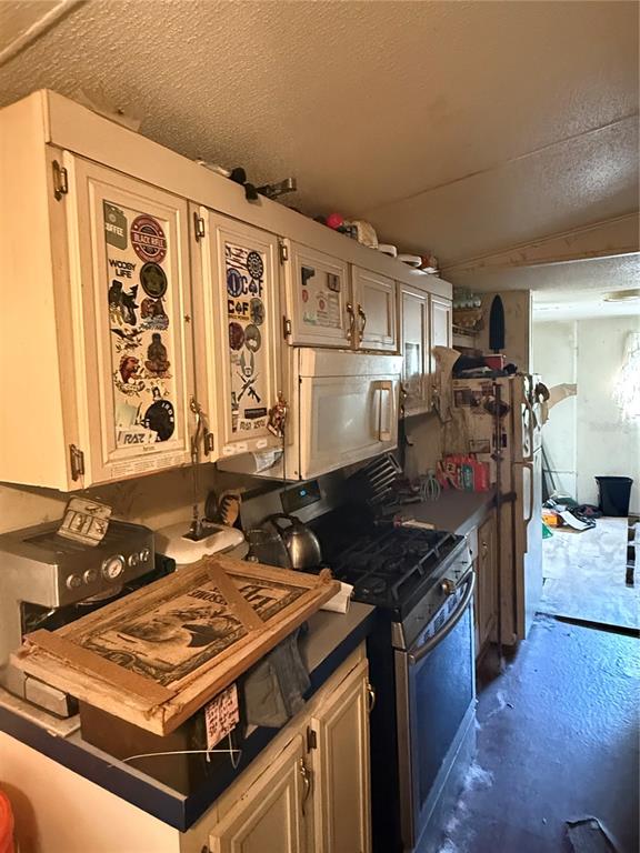 A kitchen features white cabinets with stickers, a gas range, and a stainless steel espresso machine — 108 KITTY AVENUE, INTERLACHEN, FL