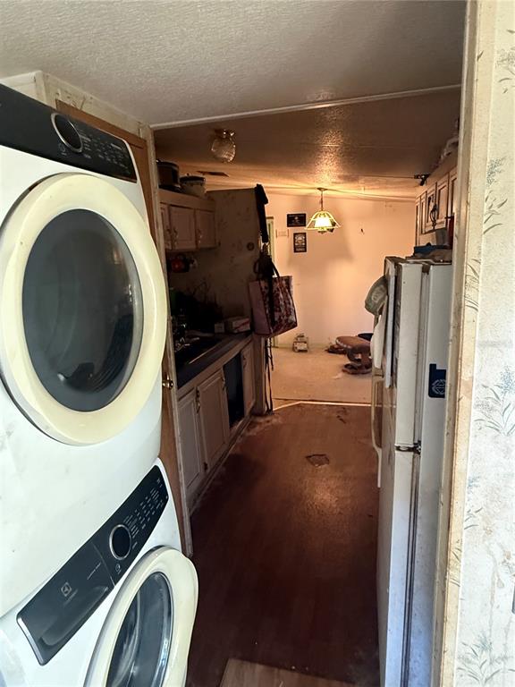 A stacked washer and dryer stand in a narrow hallway leading to a kitchen area — 108 KITTY AVENUE, INTERLACHEN, FL