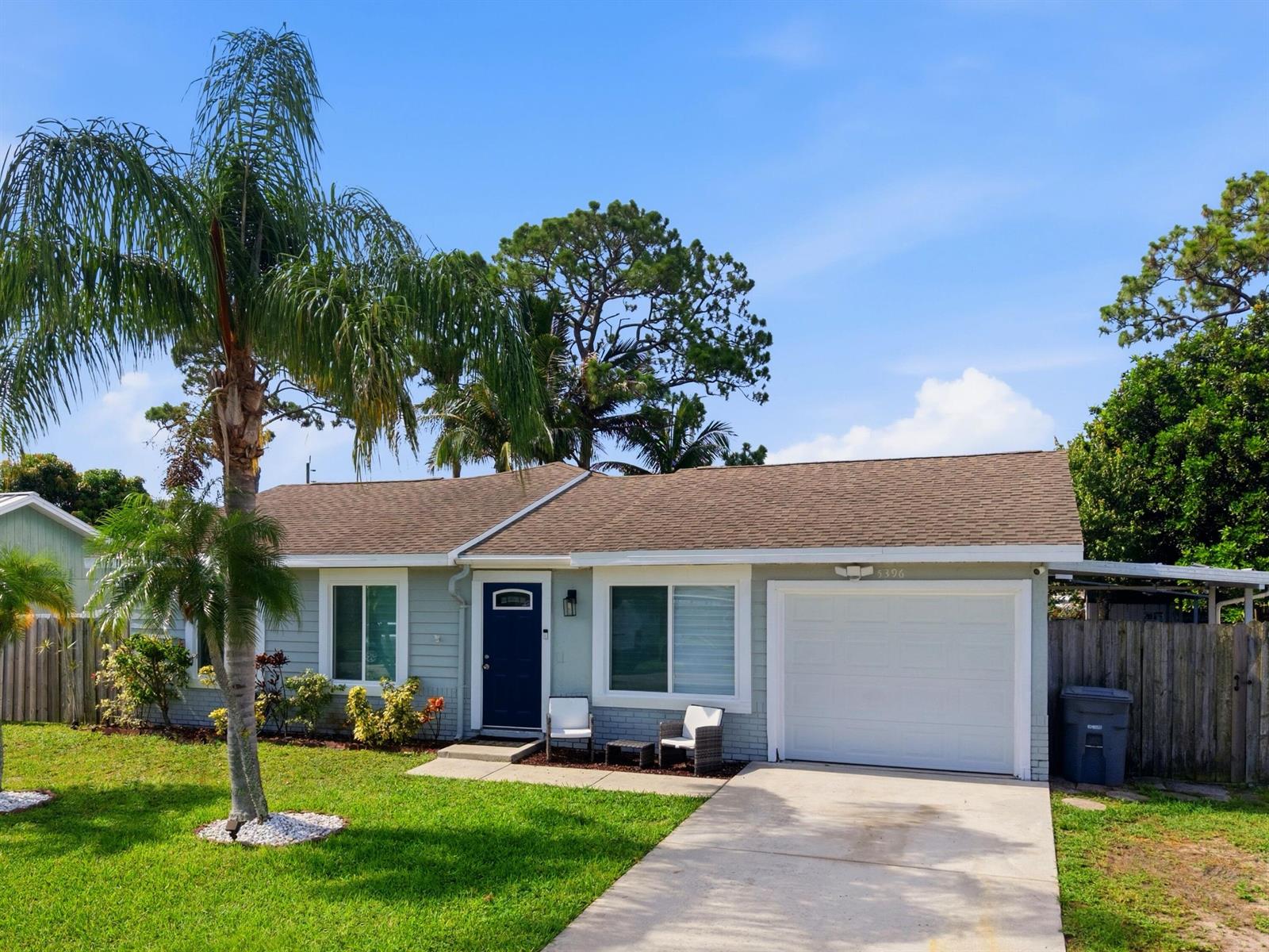 A single-story house with light green siding, a white garage door, and a palm tree — 5396 Benjamin Avenue, Boynton Beach FL 33472, BOYNTON BEACH, FL