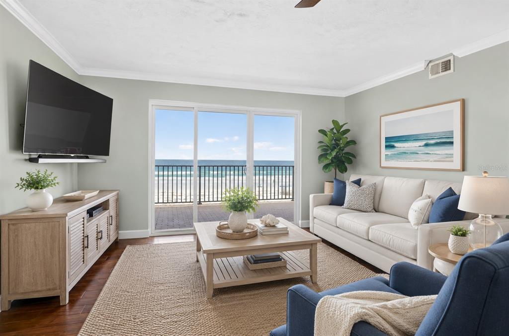 A living room with a beige sofa, blue armchair, and sliding doors overlooking the ocean — 4651 S ATLANTIC AVENUE UNIT 9203, PONCE INLET, FL